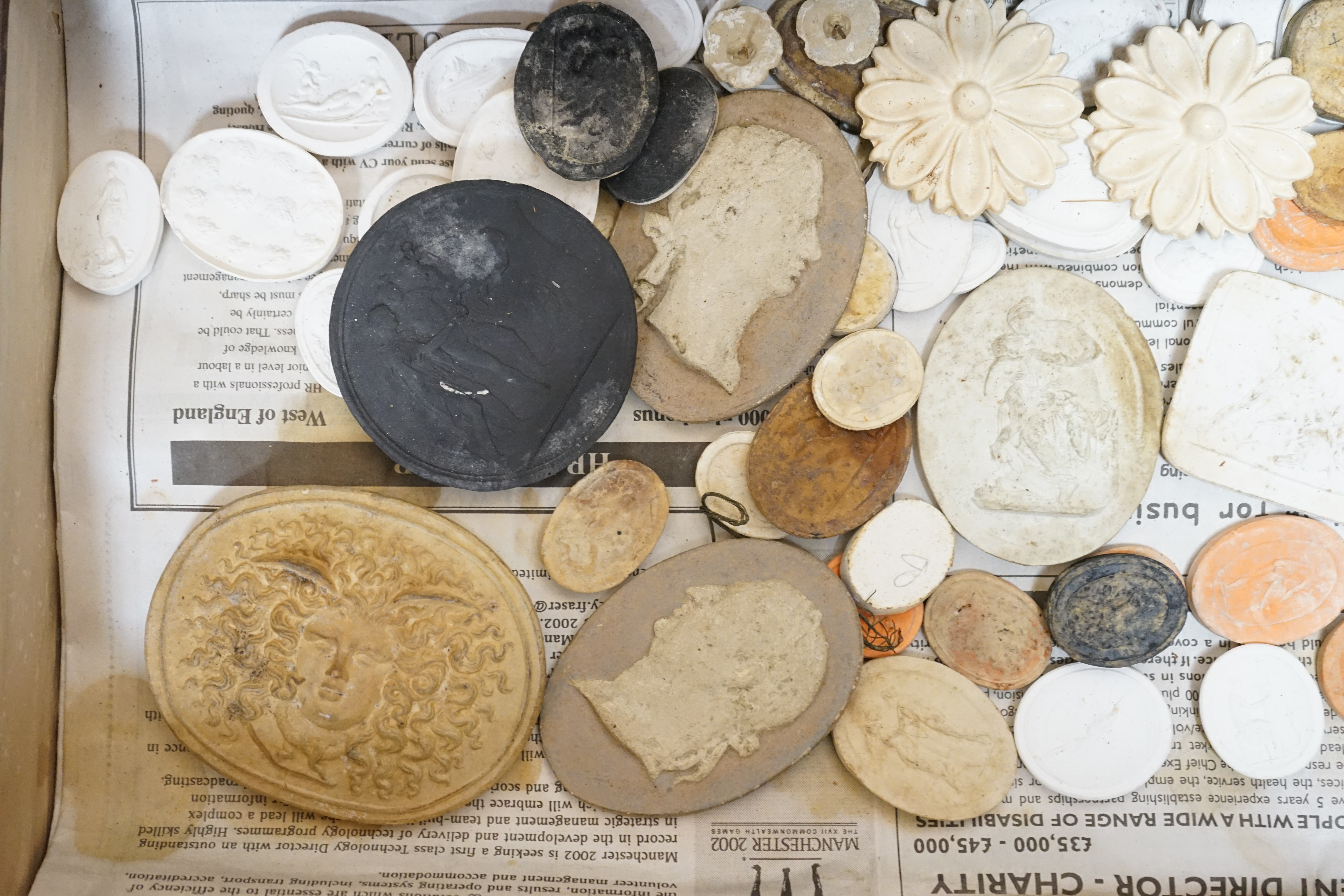 A case containing a collection of various plaster cameos and moulds. Condition - varies